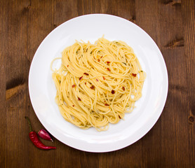 Spaghetti with garlic and chili peppers on wooden top