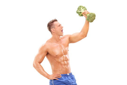 Handsome athlete lifting a broccoli dumbbell