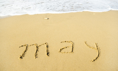 May - written in sand on beach texture
