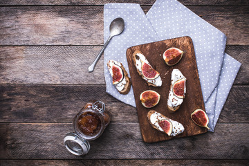 Bruschetta, jam and Sliced figs on chopping board in rustic styl