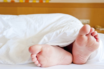 Beautiful female legs peeking out from under the blankets