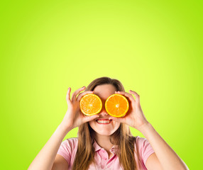 Girl with oranges in her eyes over green background