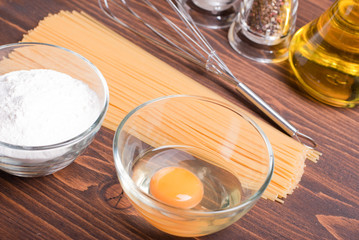 raw pasta with spices and ingredients on a brown wooden table