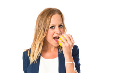 Blonde girl eating an apple over white background