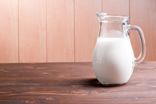 jug with milk on a light wooden table side view