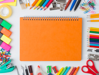 Blank orange notebook with colourful crayons