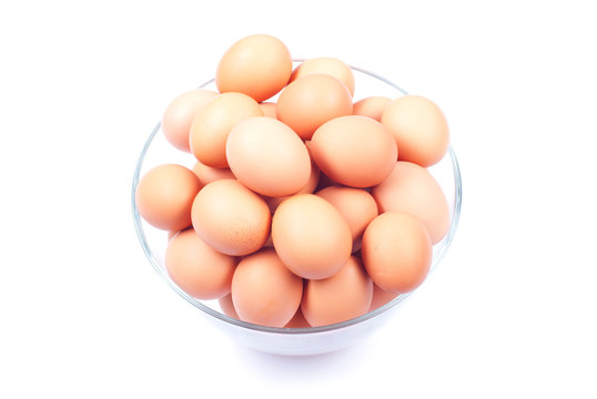 a lot of brown eggs in a large glass bowl isolated on white back