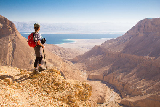 Backpacker woman standing desert mountain edge.