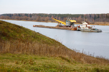 The river tow pushes the barge with a dredge