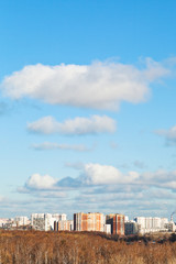 Fototapeta na wymiar white clouds in blue sky over houses in autumn day