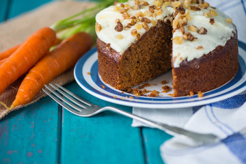 Carrot cake and cloth on table with fresh carrots