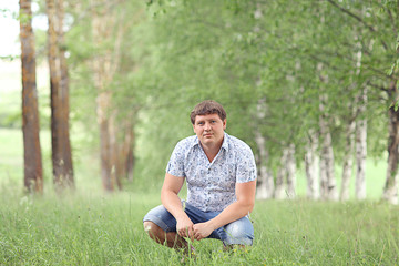 Naklejka na ściany i meble man sitting in a summer forest