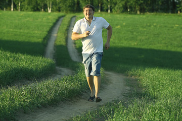 man running on the summer road in the field