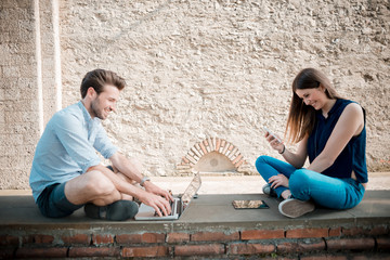 young couple using technology multitasking smarpthone tablet and