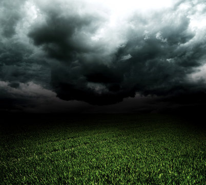 Storm dark clouds over field with grass