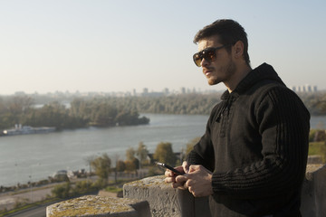 Attractive Man Posing On River Bank And Using Mobile Phone