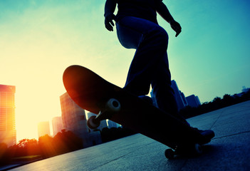 woman skateboarder skateboarding at sunrise city 