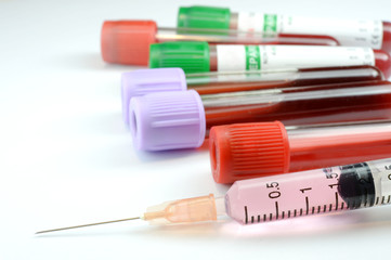 Syringe and blood test tube on white background.