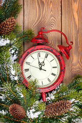 Fototapeta na wymiar Christmas clock over wooden background with snow fir tree