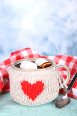 Cup of tasty hot cocoa, on wooden table, on light background