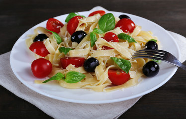 Spaghetti with tomatoes, olives and basil leaves