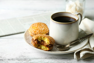Cup of coffee with tasty cookie on color wooden background
