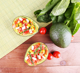 Tasty salad in avocado on table and bamboo napkin close-up