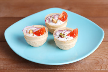 Tartlets with greens and vegetables with sauce on plate on