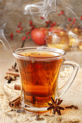 Glass of hot steaming tea among christmas decorations