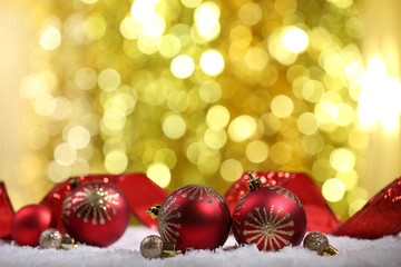 Christmas balls with red ribbon on snow on bright background