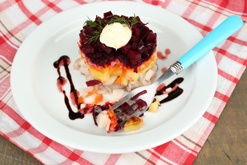 Russian herring salad on plate on wooden table background