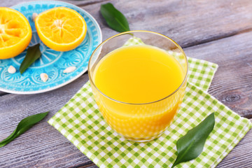 Glass of juice and ripe sweet tangerine on wooden table
