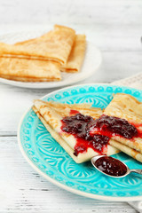 Plate of delicious pancakes with berry jam on wooden background