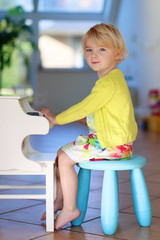 Little girl playing piano toy at home