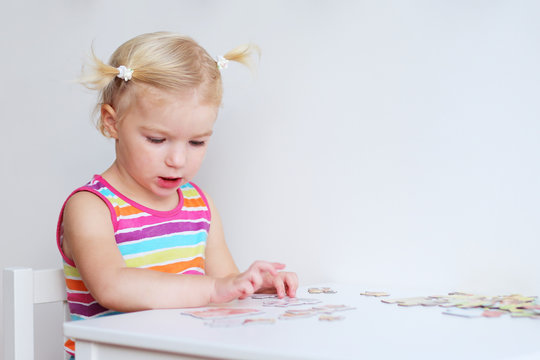 Toddler girl assembling jigsaw puzzle