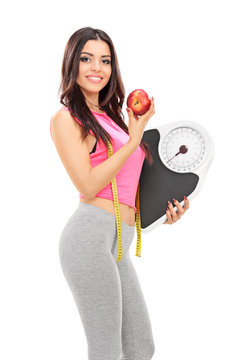 Woman holding a weight scale and an apple