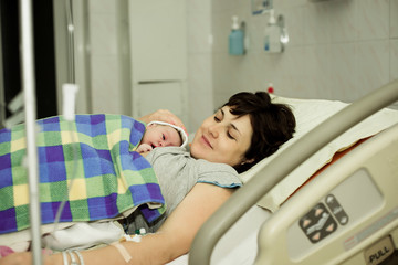 happy woman after birth with a newborn baby