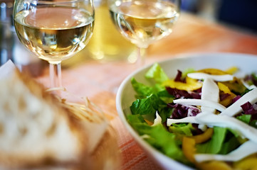 Glasses of white wine and salad on table cafe