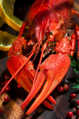 Boiled crayfishes on cutting board with lemon, pepper and parsle