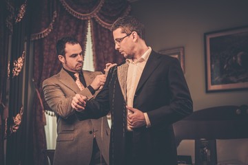Tailor measuring client for custom made suit tailoring