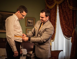 Tailor measuring client for custom made suit tailoring