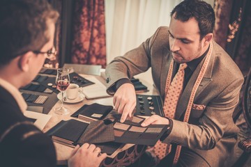 Tailor and client choosing material for custom made suit
