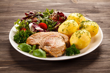 Fried pork chop, boiled potatoes and vegetable salad