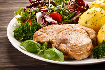 Fried pork chop, boiled potatoes and vegetable salad