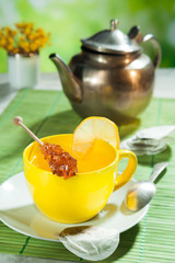 cup of tea with sugar candy and a kettle in the background