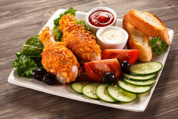 Fried chicken drumsticks and vegetables