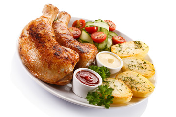 Barbecued chicken legs with baked potatoes and vegetables