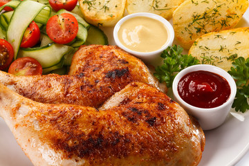 Barbecued chicken legs with baked potatoes and vegetables