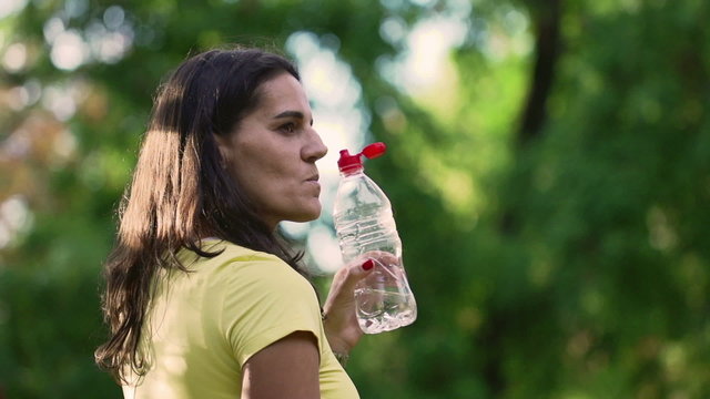 Woman drinking water in the park, slow motion 240fps, steadycam