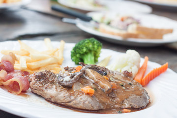Grilled steaks,  French fries, bacon and vegetable